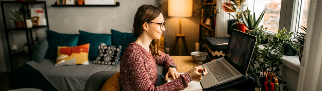 woman in glasses working on a laptop at home